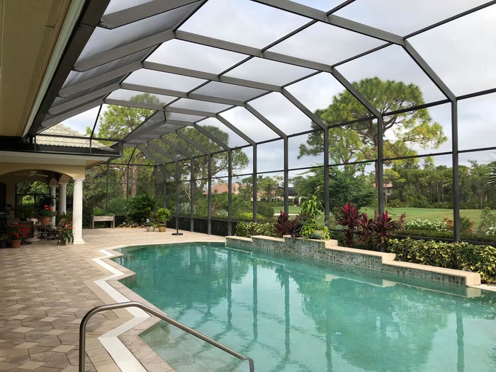 A restored bronze cage over a pool, framed by lush planting and palms.