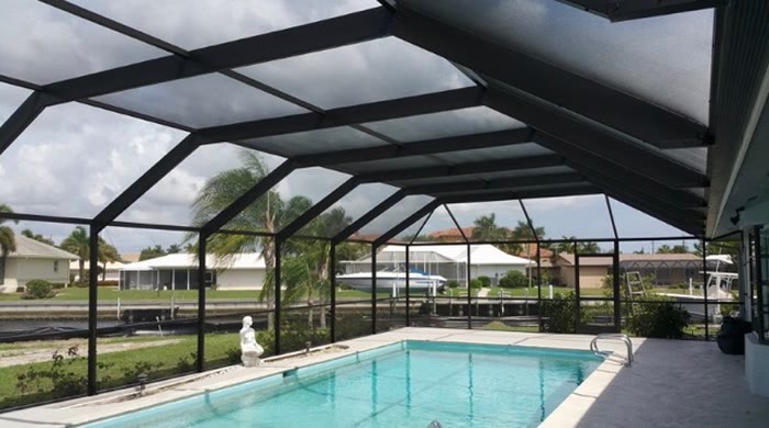 A pool and screened cage seen from the deck, water calm and screens clean.