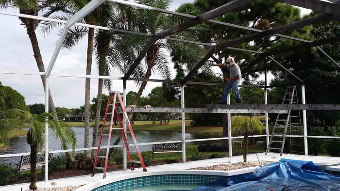 A pool completely covered with protective sheeting inside a cage, ladders standing by.