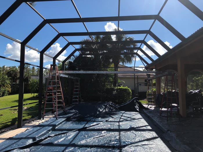 A pool enclosure masked off with sheeting across the deck before spraying.