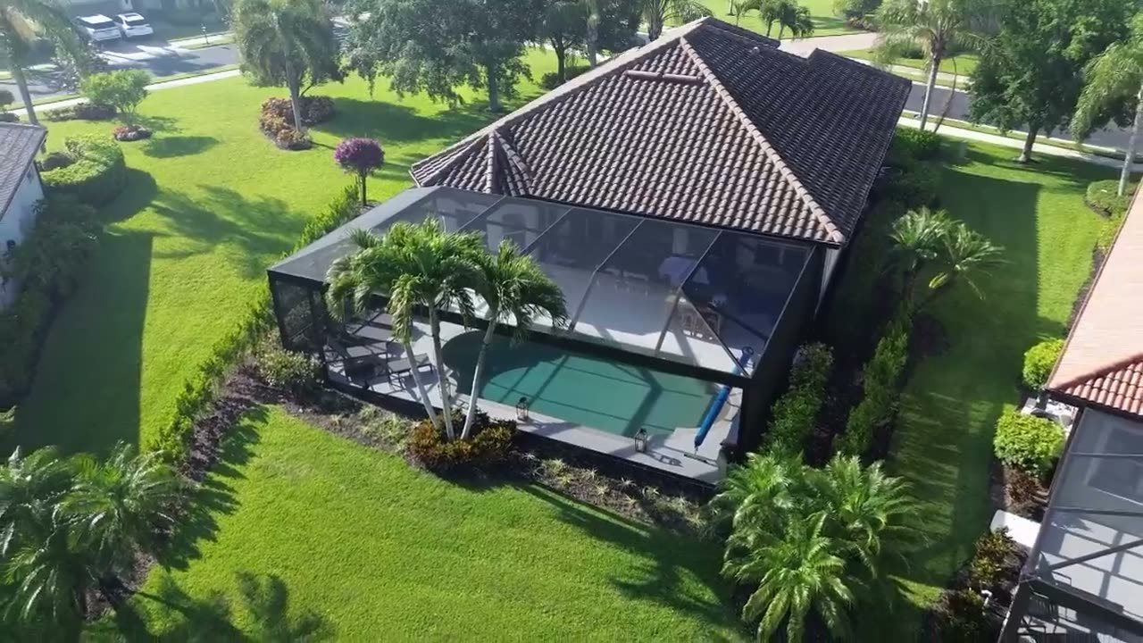A screened pool cage over a blue pool at a Florida home, seen from the air.