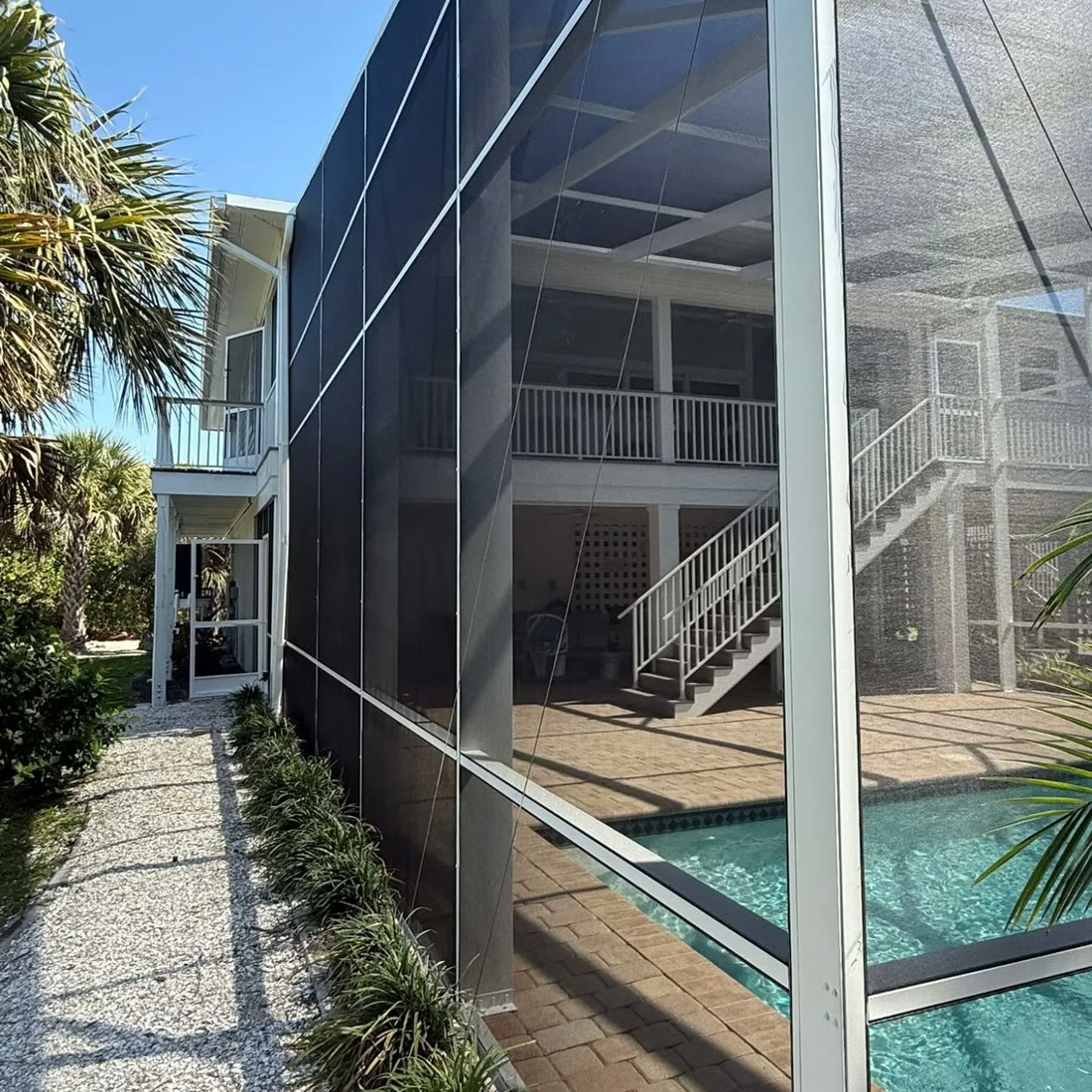 A tall two-storey screened enclosure at the back of a house, seen from the garden.